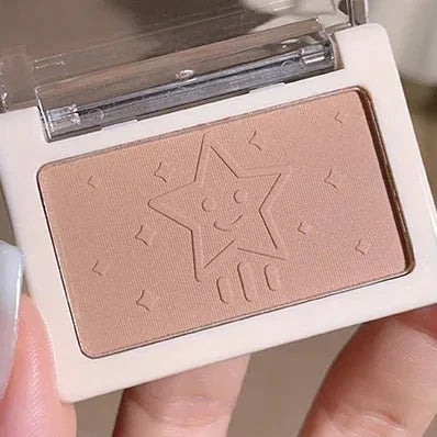 Makeup product with star design and visible brand logo held by a hand.