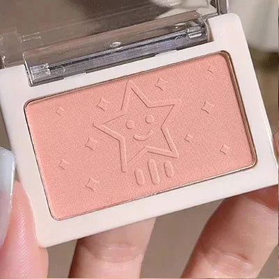 Makeup product with a star design on the packaging held by a hand.