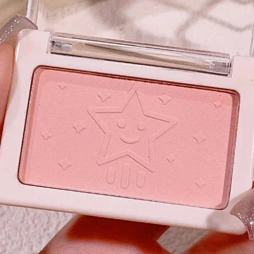 Pink blush compact with a star design on a white background